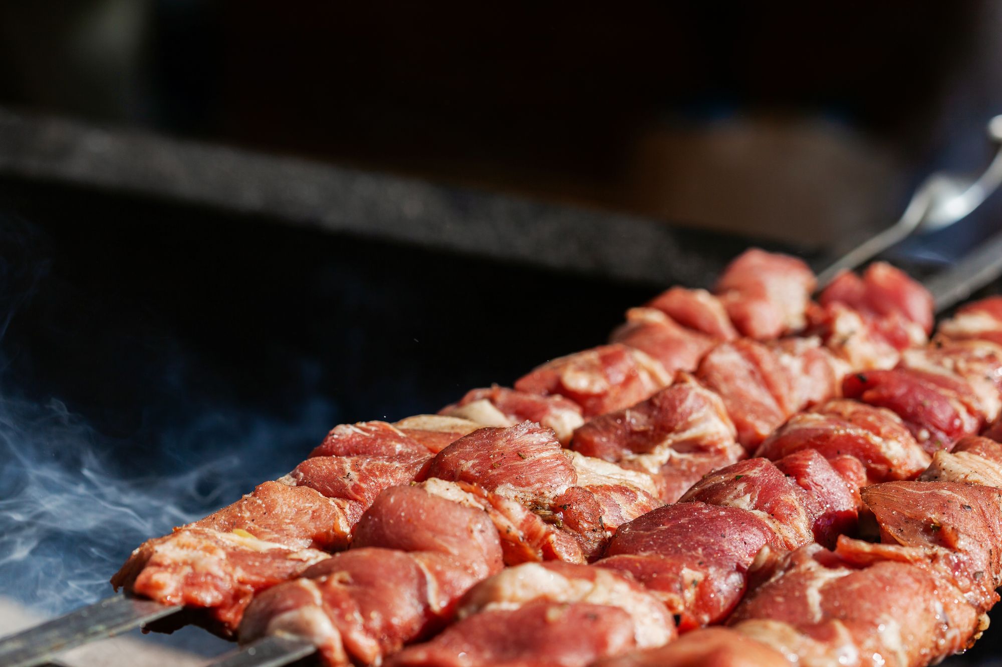 Skewers and cuts of meat sizzling over the flame of a barbecue