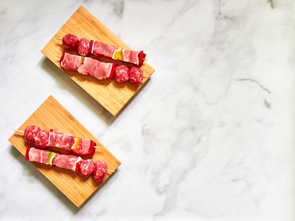 Marinated meat skewers ready to cook on a marble bench